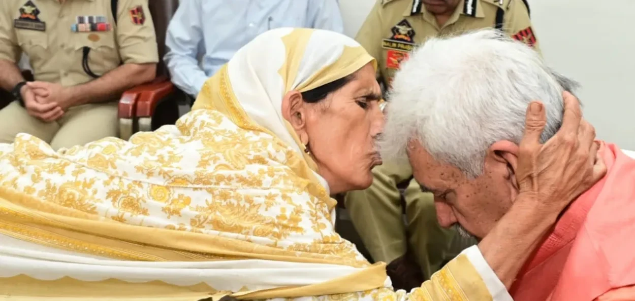 সন্ত্ৰাসবাদীৰ গুলীত পৰিয়ালৰ চাৰিজন সদস্যক হেৰুওৱা এগৰাকী মহিলাই মনোজ সিনহাৰ কপালত চুমা খাই আশীৰ্বাদ দিছে
